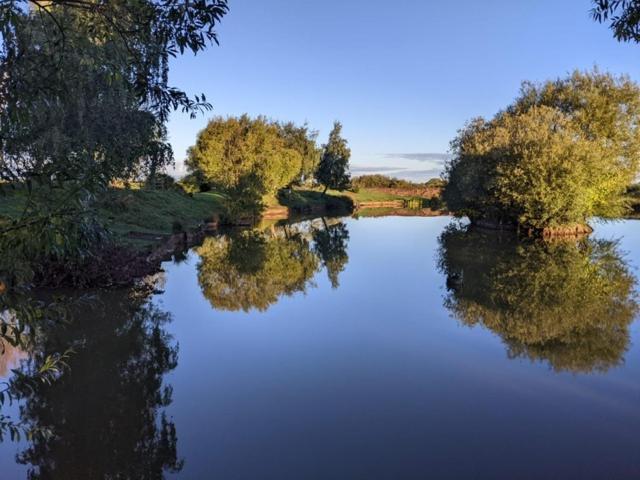 a river with trees reflecting in the water at The Shippon Barn - A delightful haven for families in Wirral