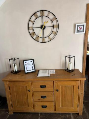 a clock on a wall above a wooden cabinet at The Shippon Barn - A delightful haven for families in Wirral