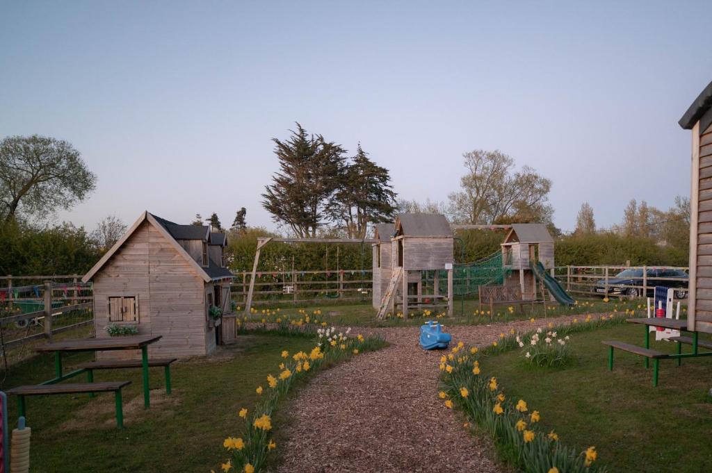 a park with a playground with flowers in the grass at The Shippon Barn - A delightful haven for families in Wirral
