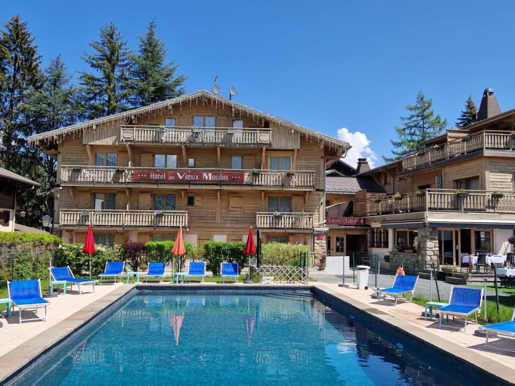 un hôtel avec une piscine devant un immeuble dans l'établissement Au Vieux Moulin, à Megève