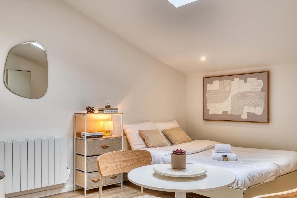 a small bedroom with a bed and a table at La Suite Sable - Cosy studio - Proche Métro B in Oullins