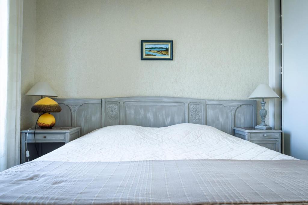 a bedroom with a white bed with two tables and two lamps at Maison Studios & Appartements Les 4 Vents in Luc-sur-Mer