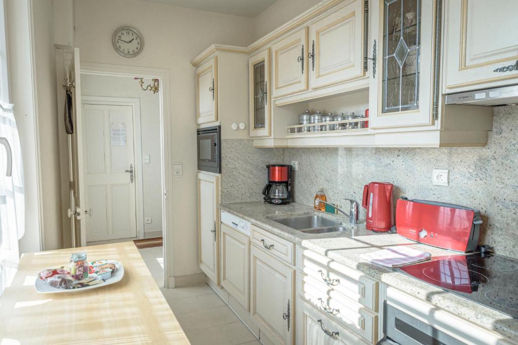 a kitchen with white cabinets and a red appliance at Maison Studios & Appartements Les 4 Vents in Luc-sur-Mer