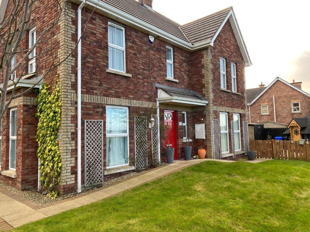 a brick house with a red door and a yard at Atlantic Bliss in Portstewart