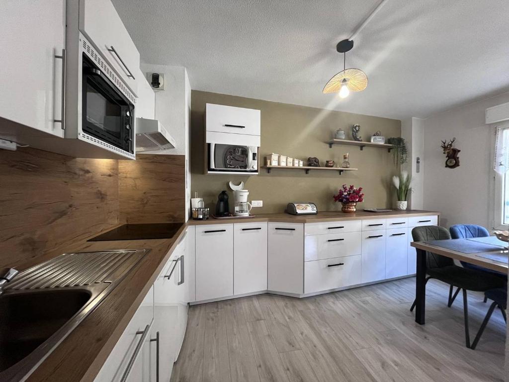 une cuisine avec des armoires blanches et une table à l'intérieur dans l'établissement Appartement à Cauterets avec terrasse et parking - FR-1-812-20, à Cauterets