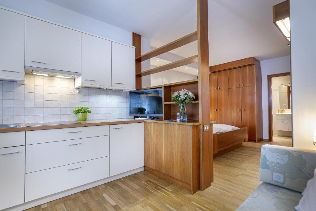 a kitchen with white cabinets and a couch at Panorama Apartments Walter in Ortisei