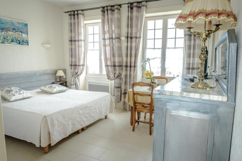 a bedroom with a bed and a table and window at Maison Studios & Appartements Les 4 Vents in Luc-sur-Mer