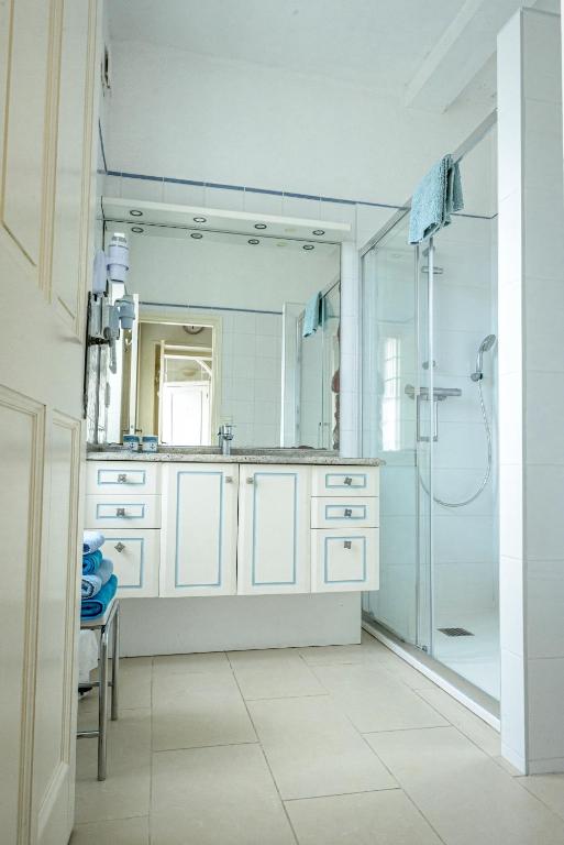 a white bathroom with a shower and a sink at Maison Studios & Appartements Les 4 Vents in Luc-sur-Mer