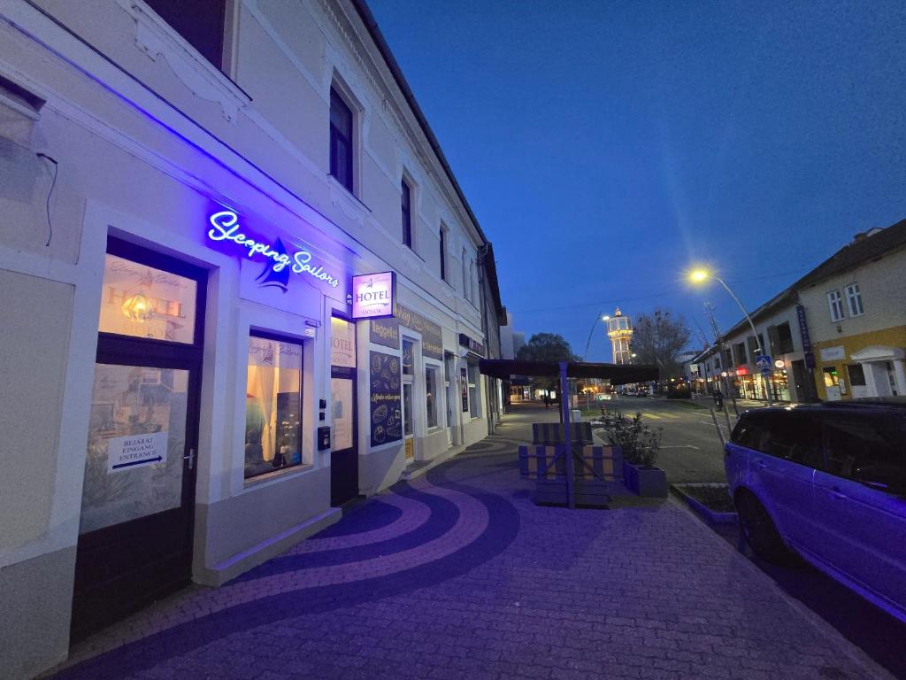 un edificio con un letrero de neón púrpura en una calle en Sleeping Sailor Boutique Hotel, en Siófok