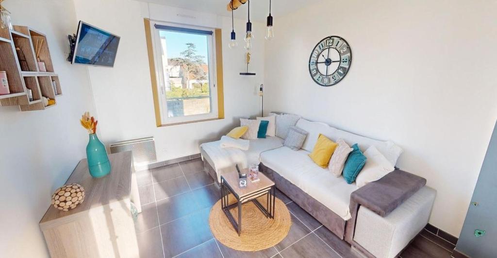 un salon avec un canapé et une horloge au mur dans l'établissement Le Petit Jersey, à Barneville-Carteret