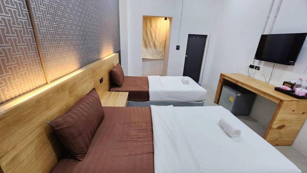 A twin room with a television, mini-fridge and narrow wooden cabinet along one wall.