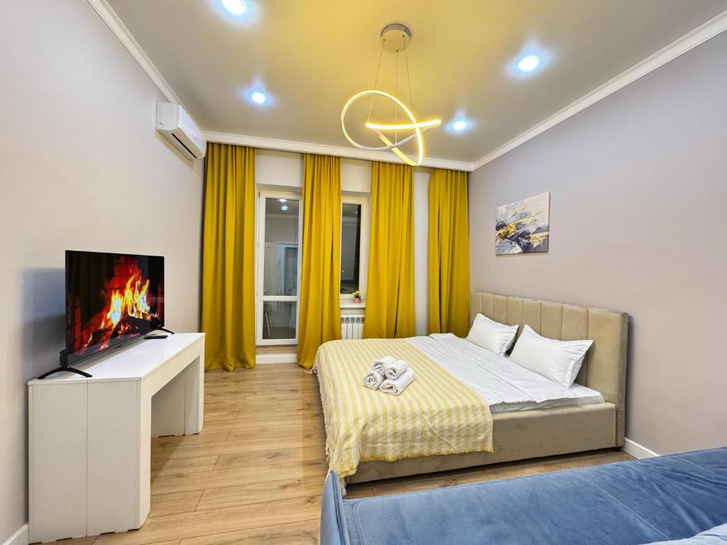 ein Schlafzimmer mit einem Bett und einem Flachbildfernseher in der Unterkunft Новая квартира рядом с ЭКСПО АЭРОПОРТОМ ПРЕЗИДЕНТСКАЯ БОЛЬНИЦА Венский 29б in Astana