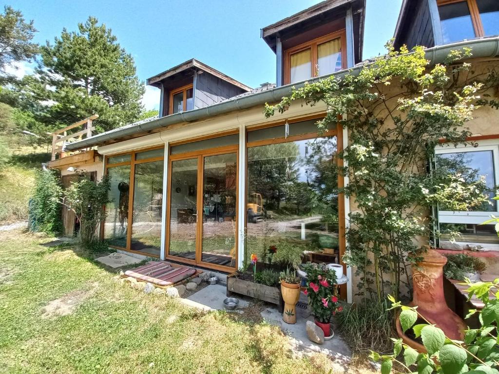 une maison avec de grandes baies vitrées et des plantes dans l'établissement Maison familliale La Abuela - lac, à Puy-Sanières