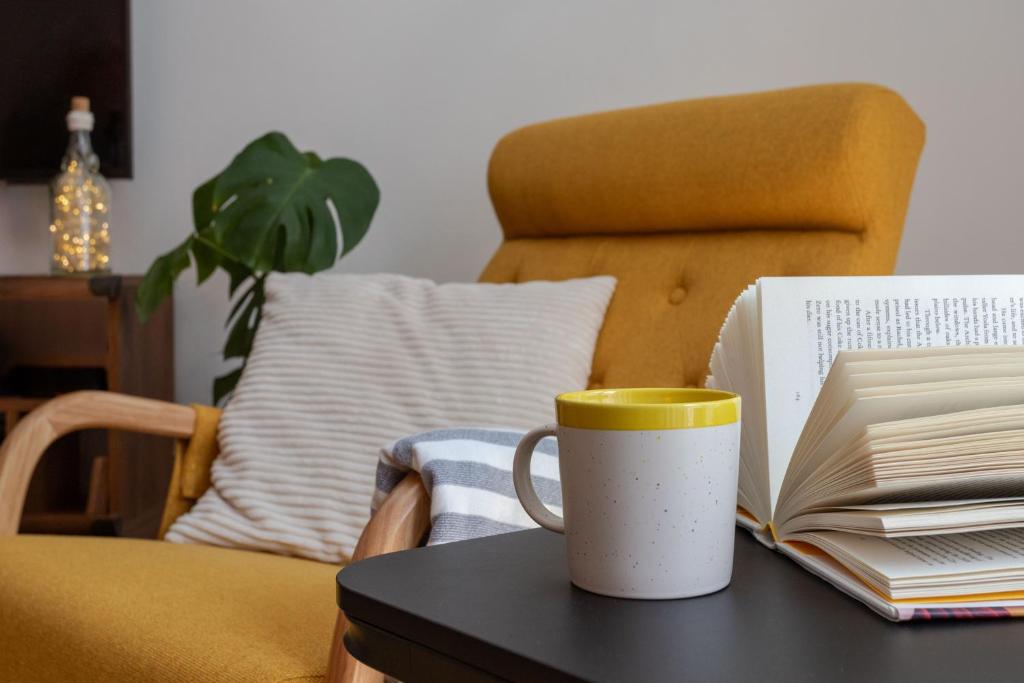 eine Kaffeetasse auf einem Tisch mit einem Buch in der Unterkunft Lush Botanic Oasis with a Boho Hideaway, Near Beach & Cafés in Lagos