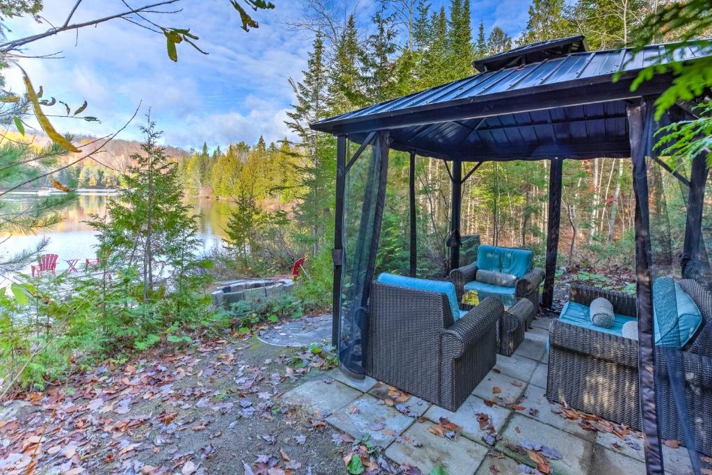 a gazebo with chairs on a patio next to a lake at Domaine La Source du Coeur in Chertsey