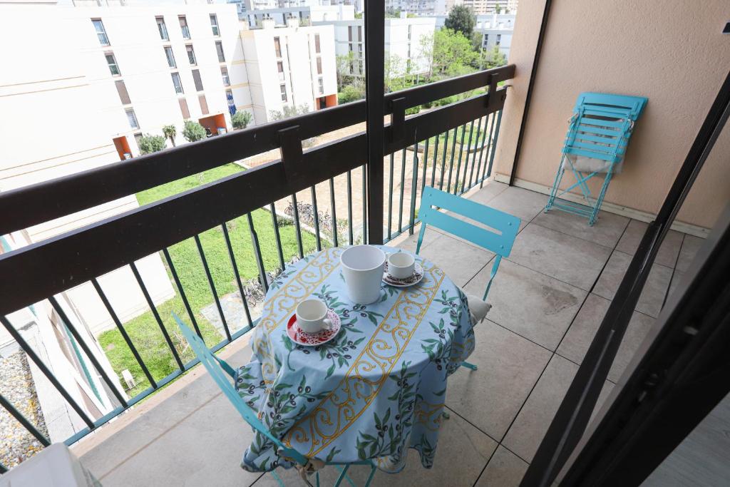 - une table avec 2 tasses et 2 chaises sur un balcon dans l'établissement Appart lumineux et climatise St Cyprien plage, à Saint-Cyprien