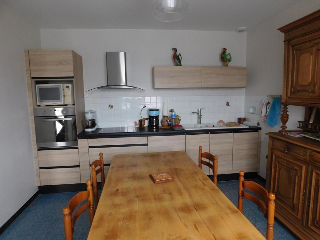 une cuisine avec une table en bois et des chaises. dans l'établissement MMR 6 personnes avec cour privée et cloturée, à Saint-Saturnin