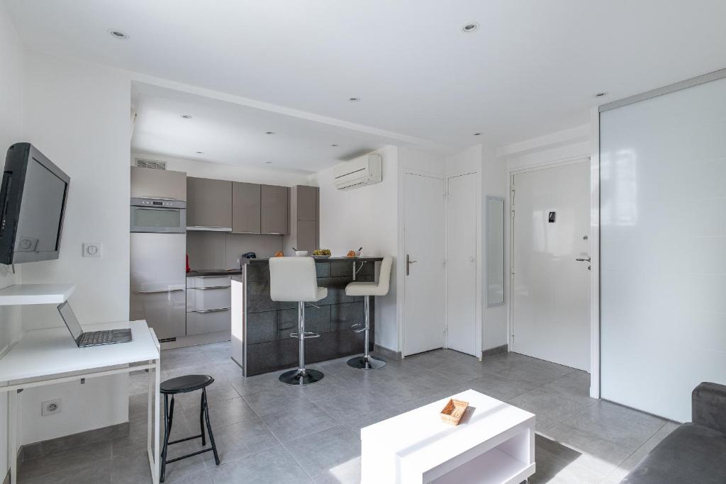 Il comprend un salon blanc avec une table et une cuisine. dans l'établissement Superbe studio-Centre-ville-Plages et Palais, à Cannes