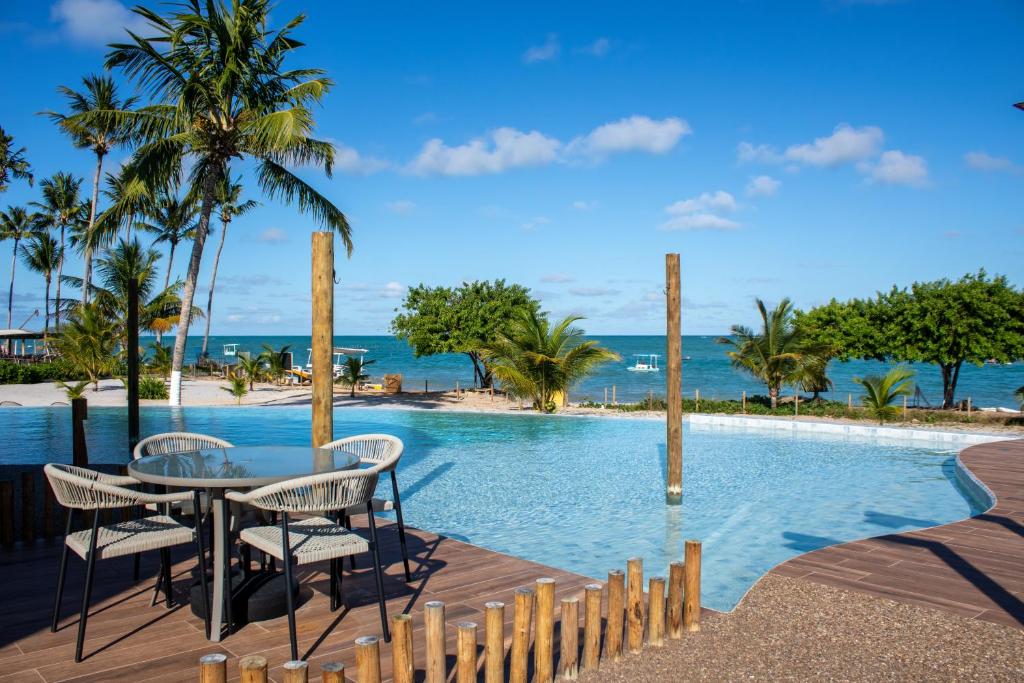 une table et des chaises à côté d'une piscine avec la plage dans l'établissement Casa Mar Kaak - Conforto e Privacidade na Praia do Marceneiro - Com Serviço, à Passo de Camarajibe