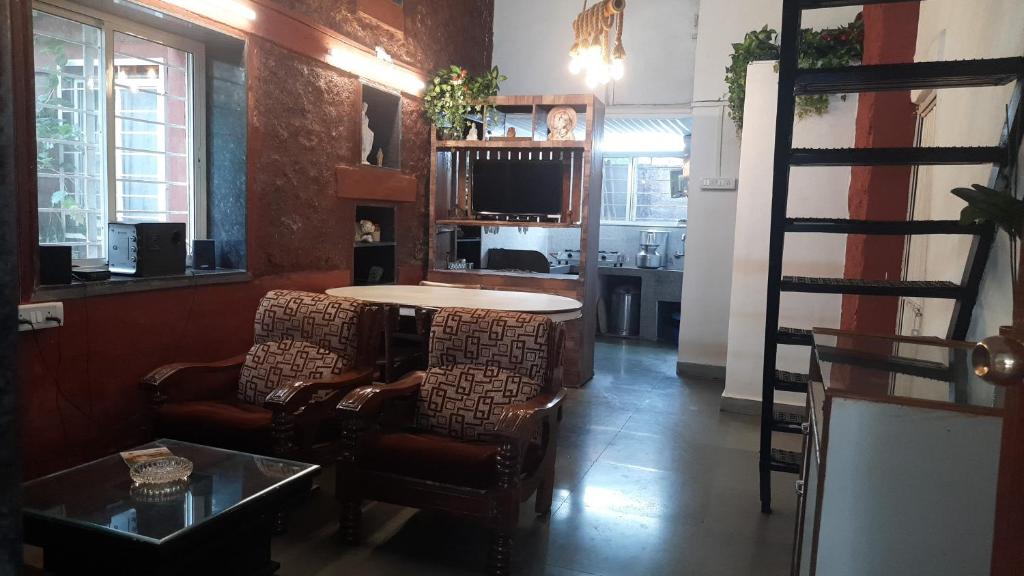 a living room with two chairs and a table at Leela Villa - Ancient Redstone Escape in Panchgani