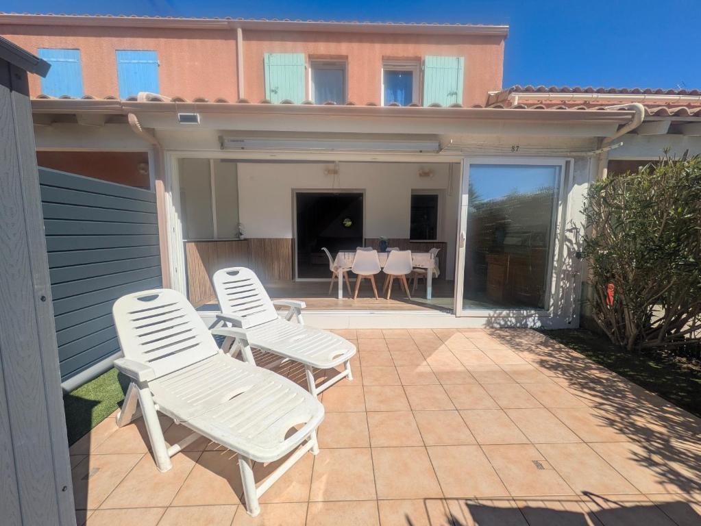 - 2 chaises blanches et une table sur la terrasse dans l'établissement Belle villa 2 chambres, veranda, terrasse parking privatif dans résidence sécurisée avec piscine commune 800 m de la mer LRCS87, à Portiragnes