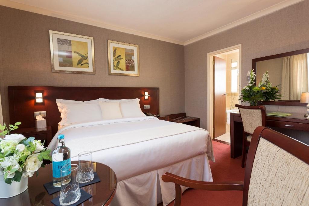 een hotelkamer met een bed en een bureau en een tafel met tafel bij Hotel Savoy in Saint Helier Jersey
