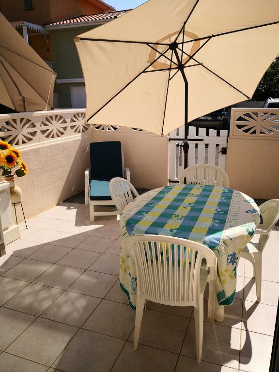 - une table, des chaises et un parasol sur la terrasse dans l'établissement Villa des Alizés, au Cap d'Agde