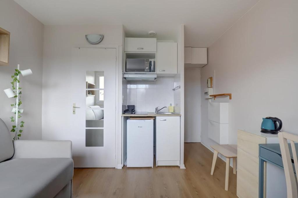 une petite cuisine blanche avec un canapé et une table dans l'établissement Studio cosy calme de 14 m2 - Plein centre, à Toulouse
