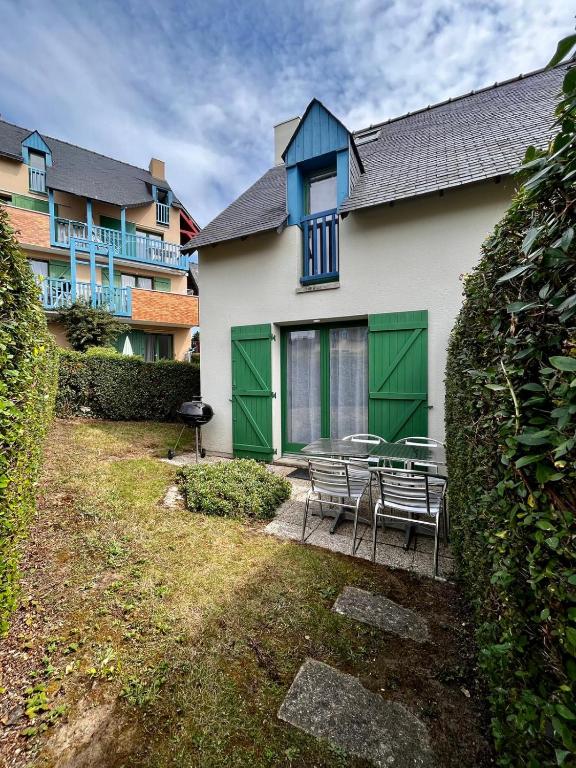 une maison avec des portes vertes, une table et des chaises dans l'établissement villa rotheneuf, à Saint-Malo