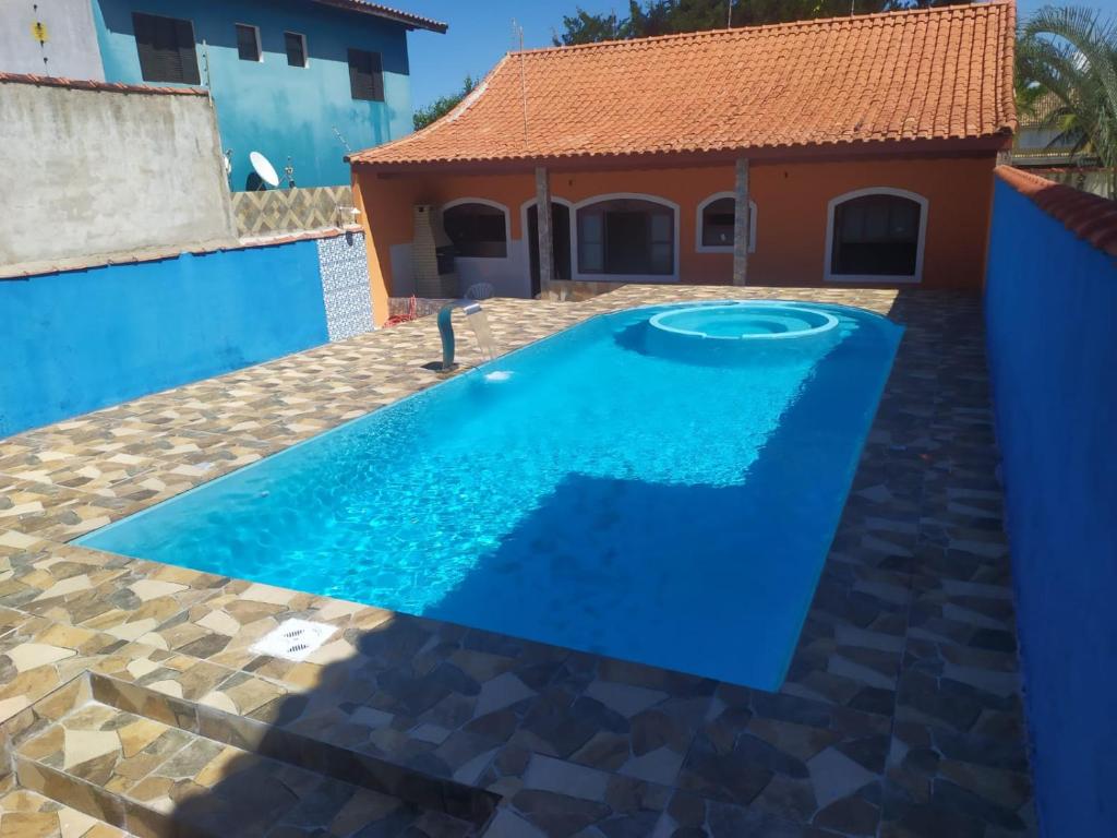 a blue pool in front of a house at Casa Praia com piscina Itanhaem in Itanhaém