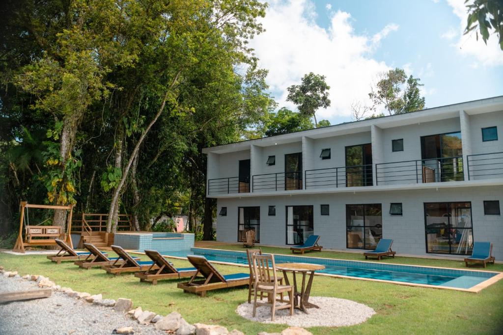 a resort with a pool and chairs and a building at BoraMar Flats in Caraguatatuba