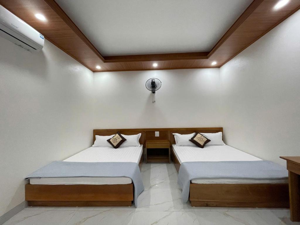 two beds in a room with white walls at Thảo Vân hotel in Sầm Sơn