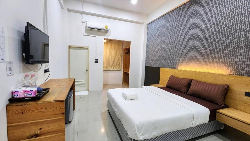 A bright double room with a wall-mounted TV, dresser, and air conditioning.