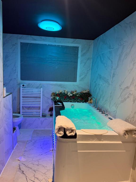 une grande salle de bain avec une baignoire et un lavabo dans l'établissement Logements jacuzzi silencieux, à Deuil-la-Barre