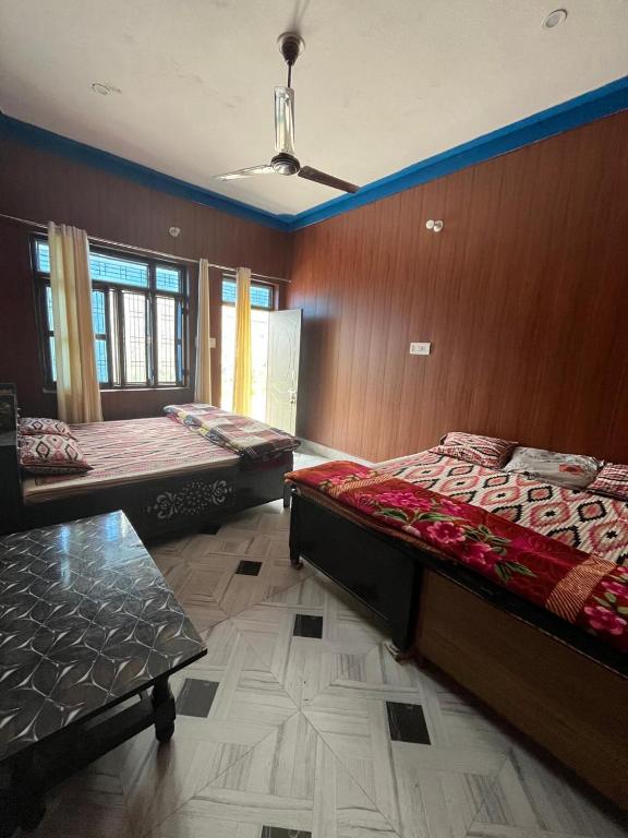 two beds in a room with wooden walls at Kartikey homestay and restaurant in Gopeshwar