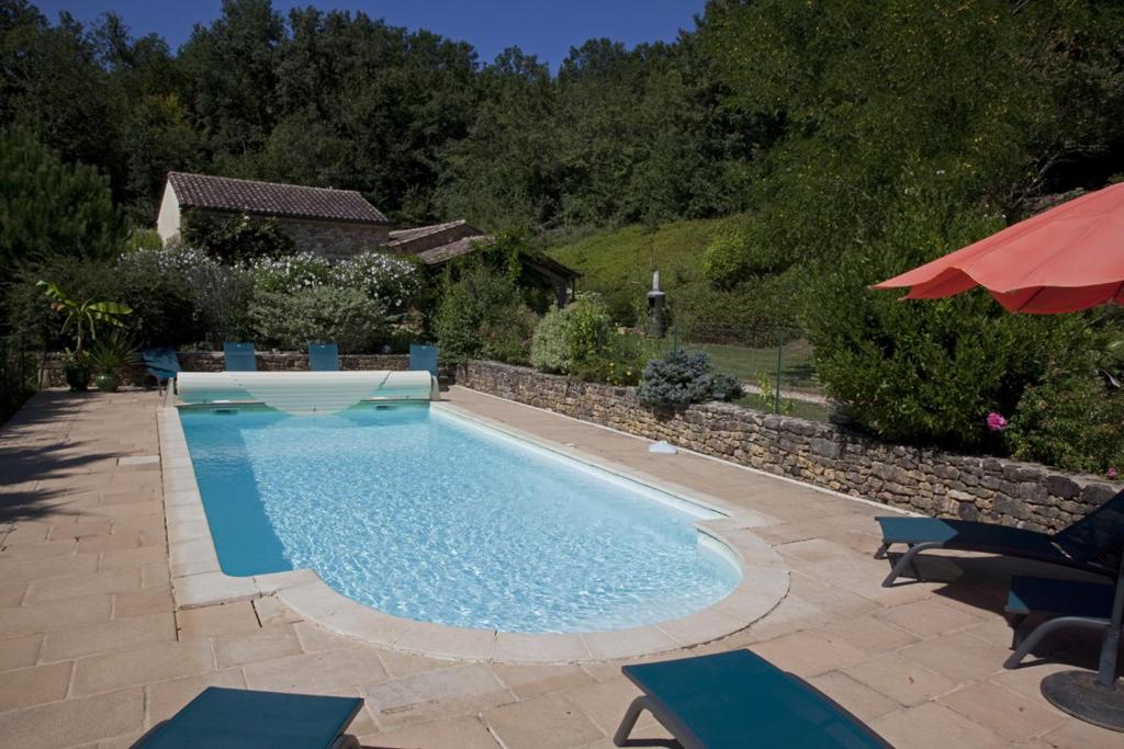 une piscine avec des chaises et un parasol dans l'établissement Maison à la campagne avec piscine privée, à Marsalès