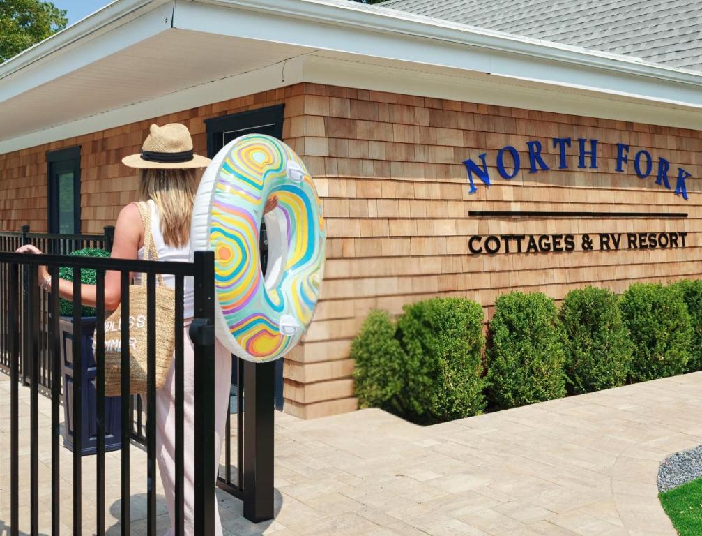 a woman standing in front of a building with a donut at North Fork Resort in Greenport