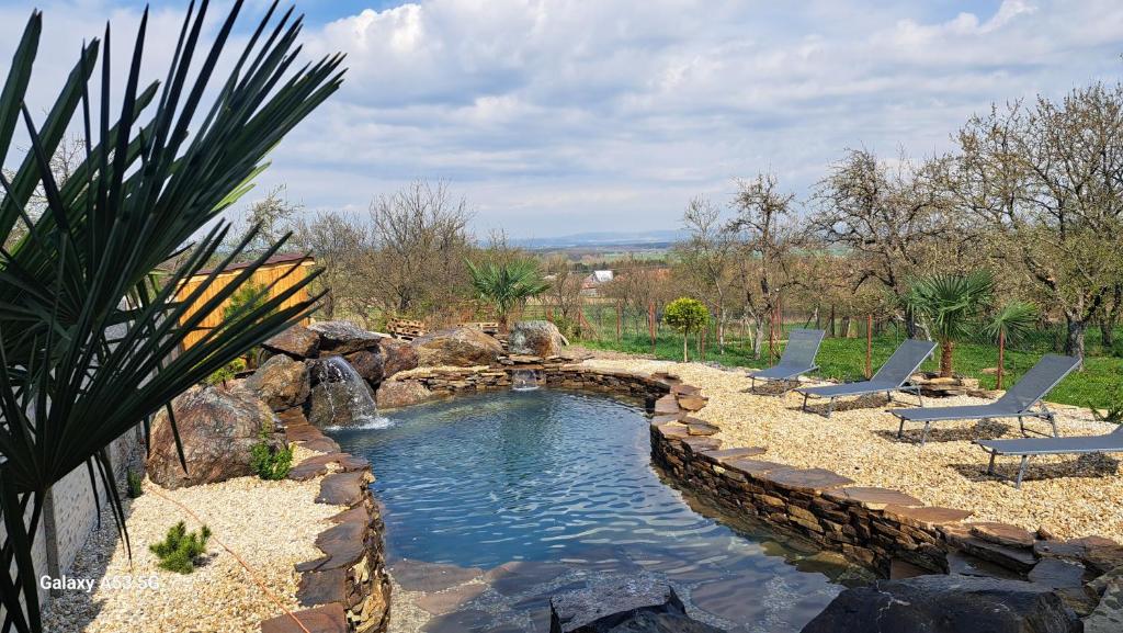 a swimming pool with two chairs and a rock wall at jazer in Prievaly