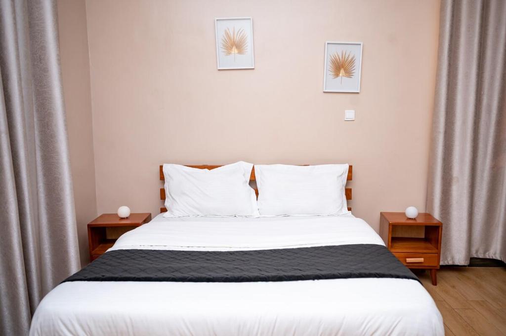 un dormitorio con una cama con sábanas y almohadas blancas en 1 Bedroom Apartment in Kampala - WiFi - PowerBack - Workspace, en Kampala