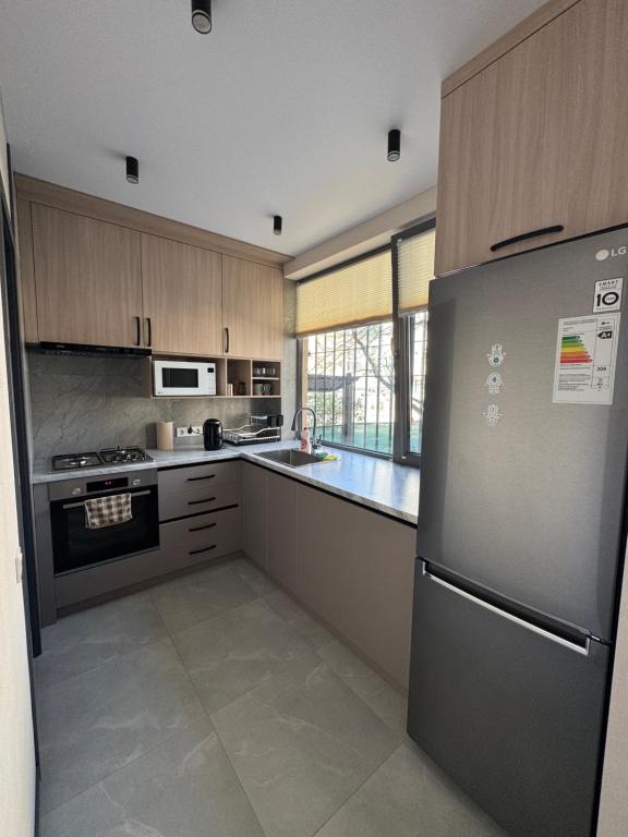 a kitchen with a refrigerator and a stove top oven at Cozy Apartment in the Heart of Fergana in Fergana