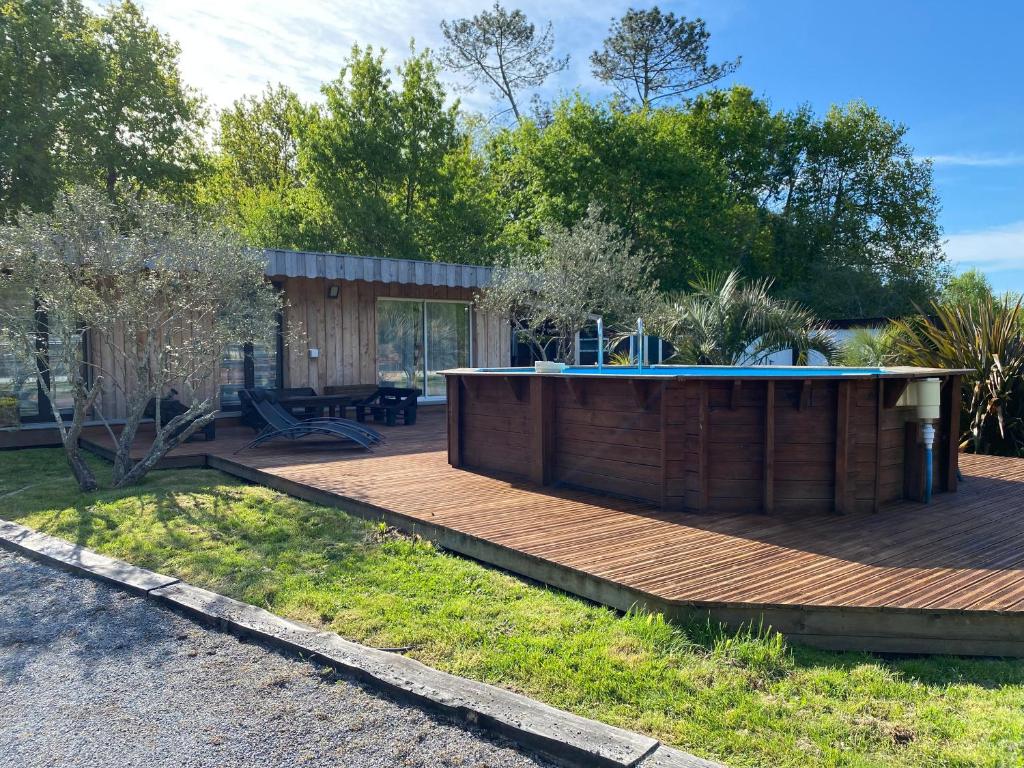 une terrasse en bois avec une piscine dans une maison dans l'établissement Maison atypique - lisière de forêt - Bassin Arcachon, à Audenge