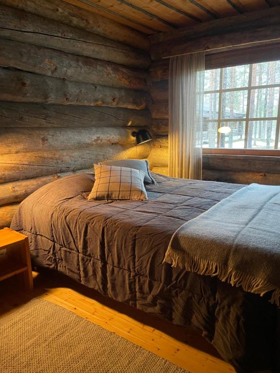een slaapkamer met een bed in een blokhut bij Villa Havu in Kuusamo