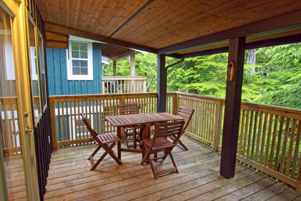 a wooden deck with a table and chairs on it at Tide and Trail- Cabin in Ucluelet in Ucluelet