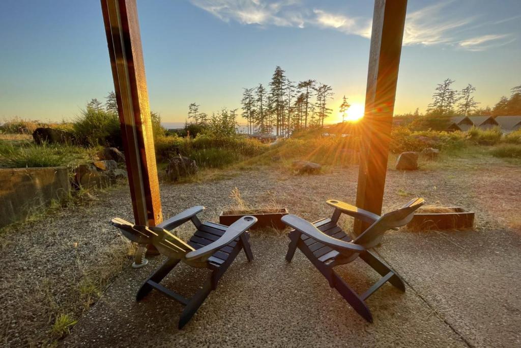 duas cadeiras sentadas em frente a uma janela com o pôr do sol em Big Beach Escape - Ucluelet - Sleeps 6 - Pet Friendly em Ucluelet