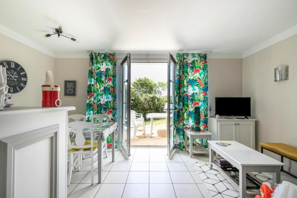 - un salon avec des rideaux, une table et des chaises dans l'établissement Les Maisons de Port Bourgenay - maeva Home - Maison climatisée 3 pièces 6 personnes - Prestige MAE-7481, à Saint-Hilaire-de-Talmont