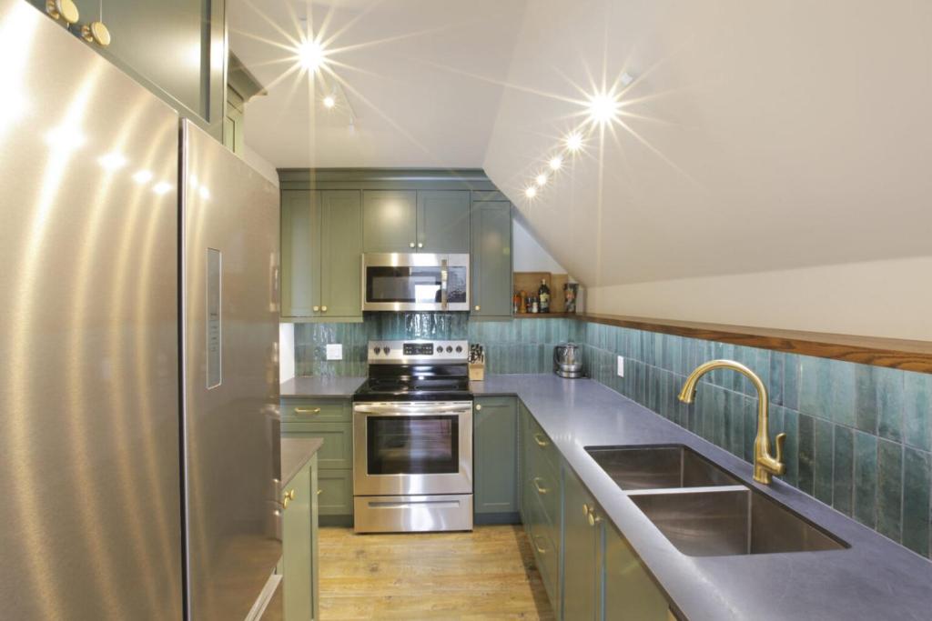 uma cozinha com armários verdes e electrodomésticos de aço inoxidável em Raven Lady #202- Ucluelet, Sleeps 4, Pet Friendly em Ucluelet