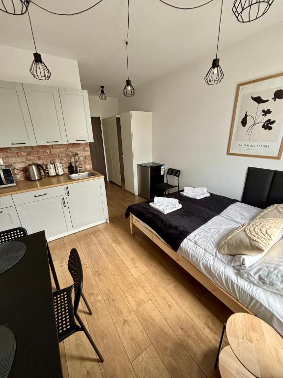 a bedroom with a large bed and a kitchen at Apartament Kamionka Piast in Opole