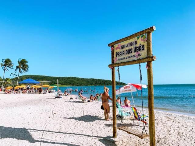 a sign on a beach with people in the water at Loft 11, caminho do mirante in Iguaba Grande
