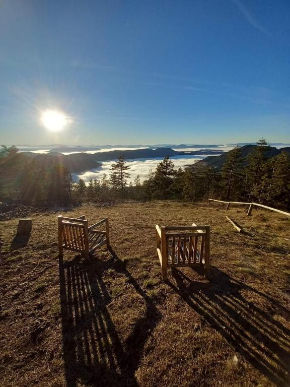 a bench sitting on top of a field with a view at Koliba Dobro drvo Off-Grid Cabin Zlatibor in Zlatibor