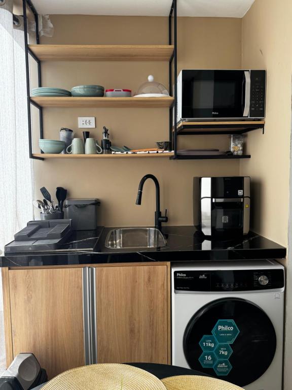 a kitchen with a sink and a microwave and a dishwasher at Bela Curitiba Aparthotel in Curitiba